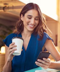 Woman holding a coffee while looking at her phone