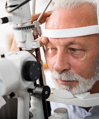 man with a white beard and a white shirt is getting his eyes looked at