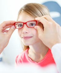 woman in glasses looking at a young girl's eye
