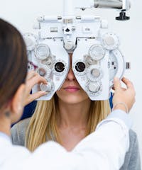 woman with glasses on her eyes looking at a man with an eye exam