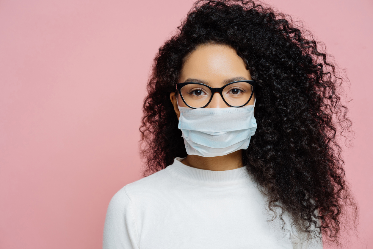 African woman wearing dark glasses and a blue face mask