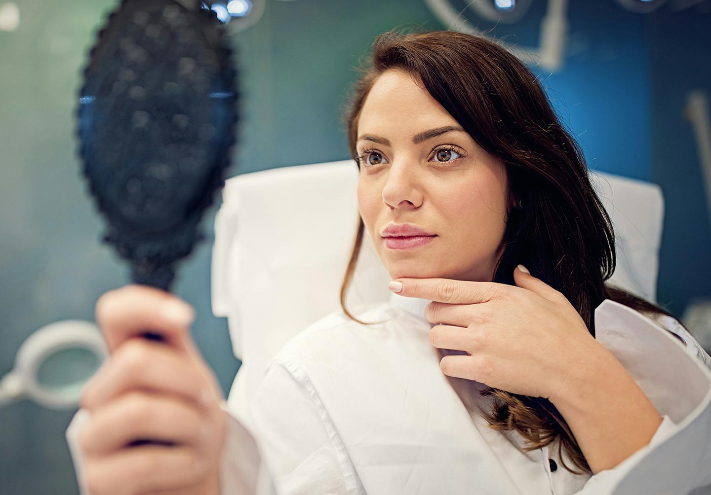 Woman looking in mirror after botox in Denver