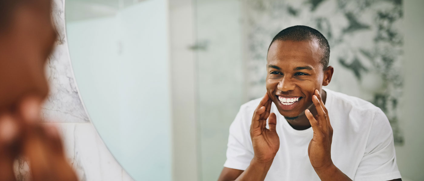 Man smiling in the mirror after receiving Botox from Genesis Lifestyle Medicine.