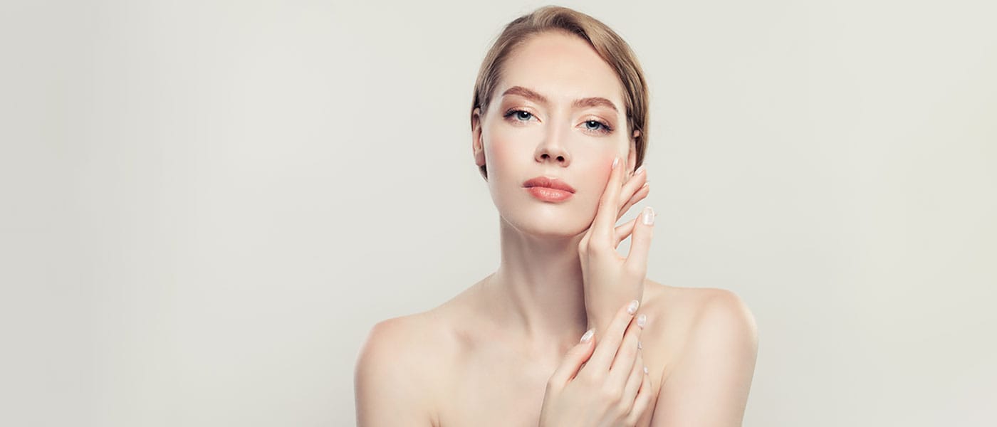 Woman touching her skin after receiving dermal fillers from Genesis Lifestyle Medicine.