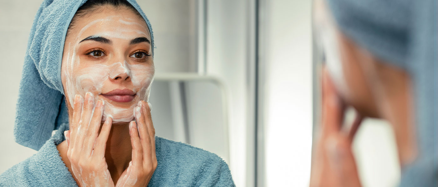 Woman applying skin care product to her face from Genesis Lifestyle Medicine.