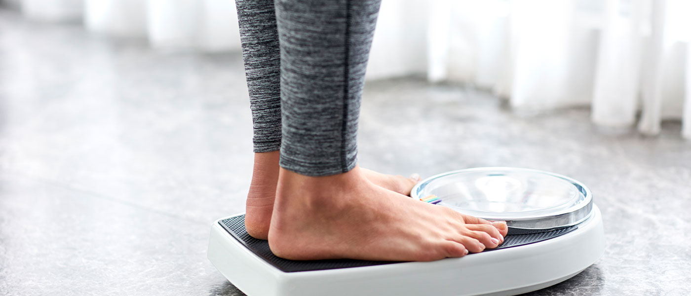 woman standing on a scale after weight loss program from Genesis Lifestyle Medicine