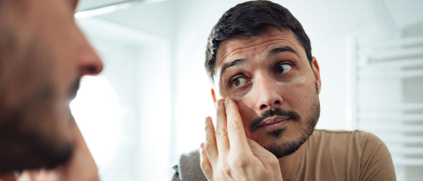 Man looking in mirror after receiving dermal filler at Genesis Lifestyle Medicine.