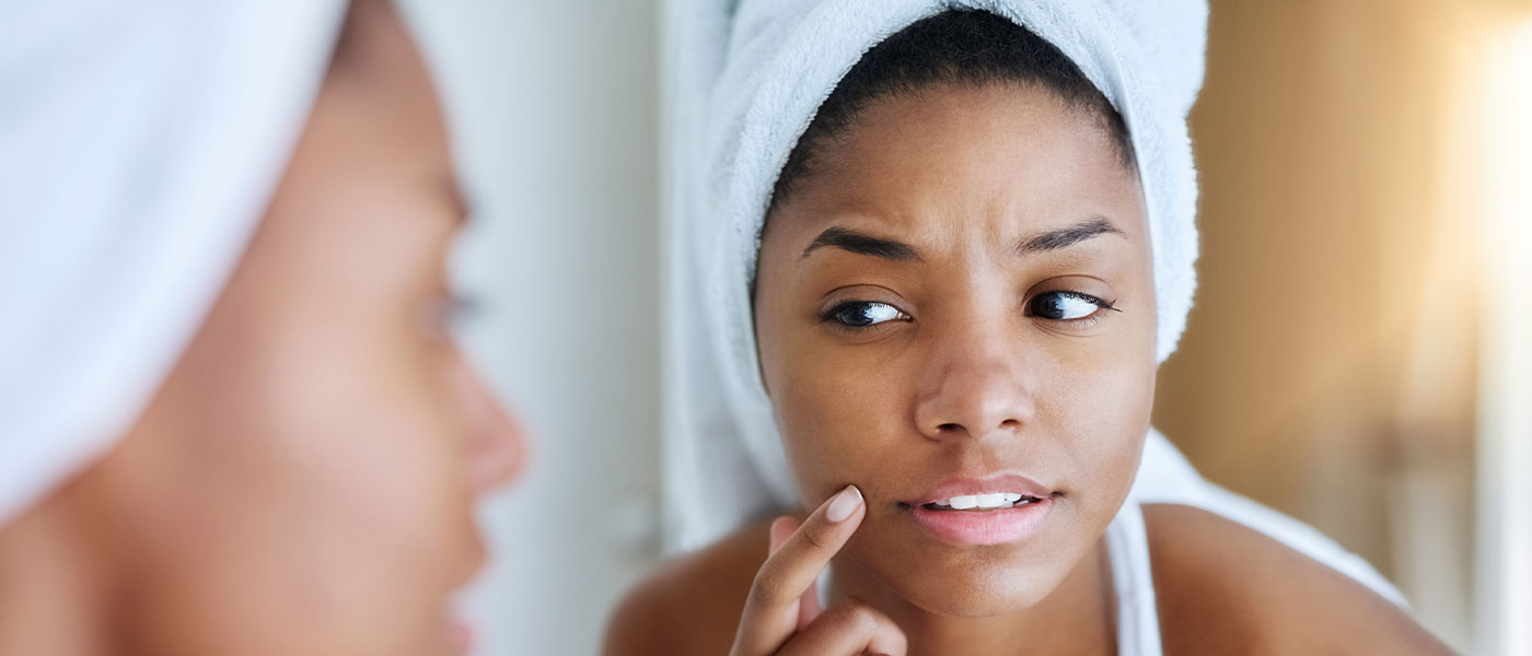 Woman looking in the mirror after a vampire facial from Genesis Lifestyle Medicine.