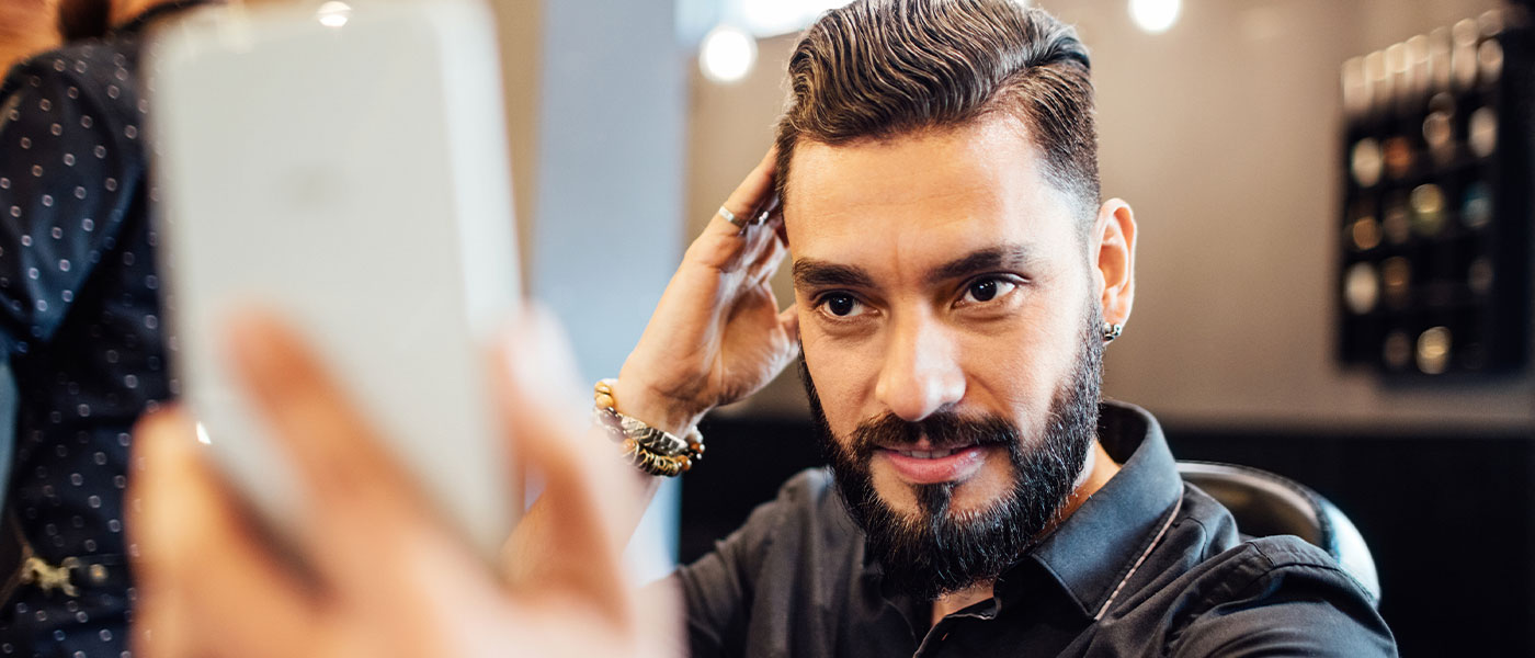 Man looking in mirror after hair restoration at Genesis Lifestyle Medicine.