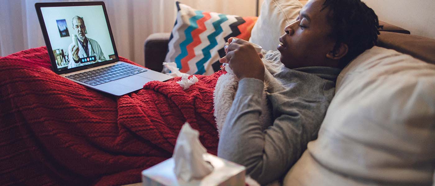 Sick man on a laptop having a telehealth consultation with Genesis Lifestyle Medicine.