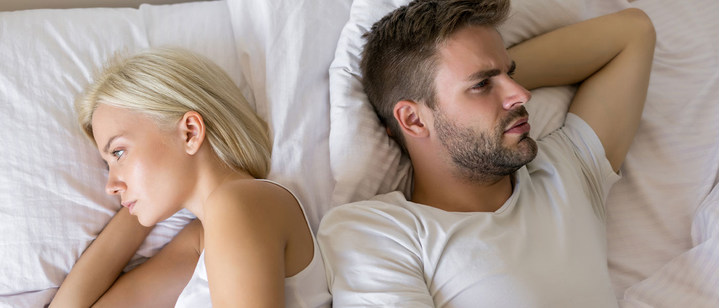 distressed couple in bed considering ED treatment from Genesis Lifestyle Medicine