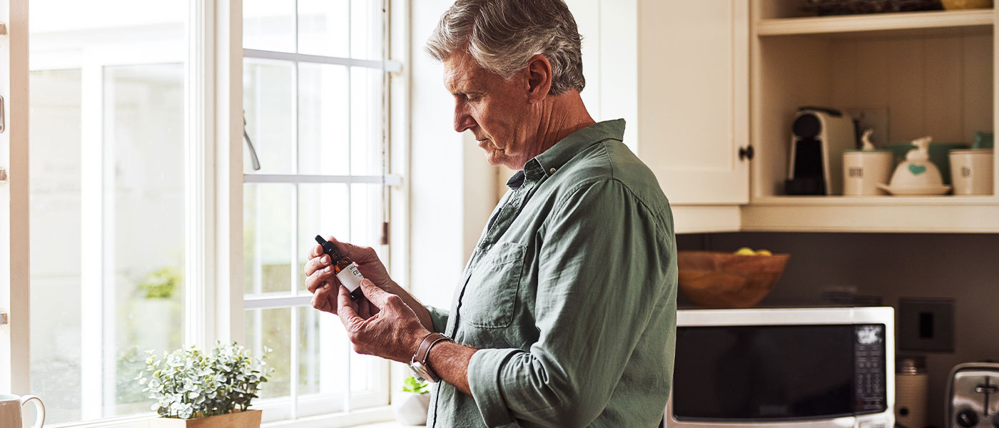 man holding THC bottle and considering ED treatment from Genesis Lifestyle Medicine