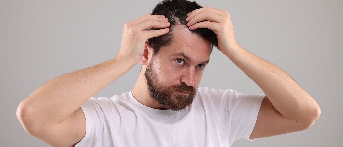 Man checking his hair after taking GLP-1 medication from Genesis Lifestyle Medicine.