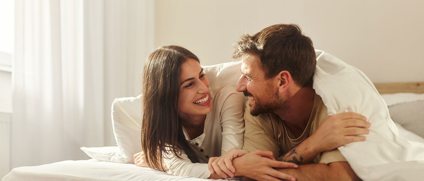 Happy couple in bed after ED treatment from Genesis Lifestyle Medicine.