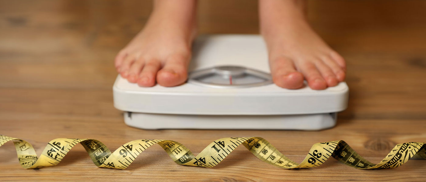 Client on a scale after taking GLP-1 medication at Genesis Lifestyle Medicine.