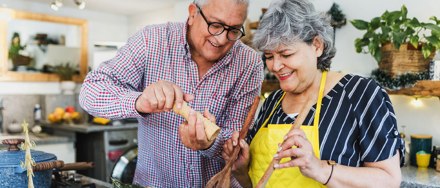 Happy couple making dinner after receiving hormone therapy at Genesis Lifestyle Medicine.