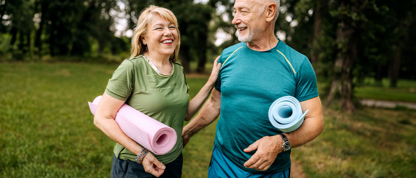 Happy couple holding yoga mats after medical weight loss program from Genesis Lifestyle Medicine.