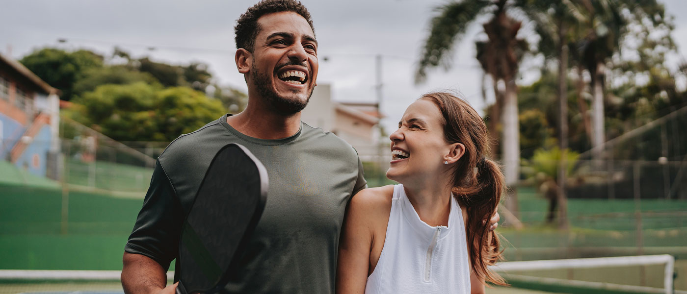 Happy couple playing tennis after successful weight loss program from Genesis Lifestyle Medicine.