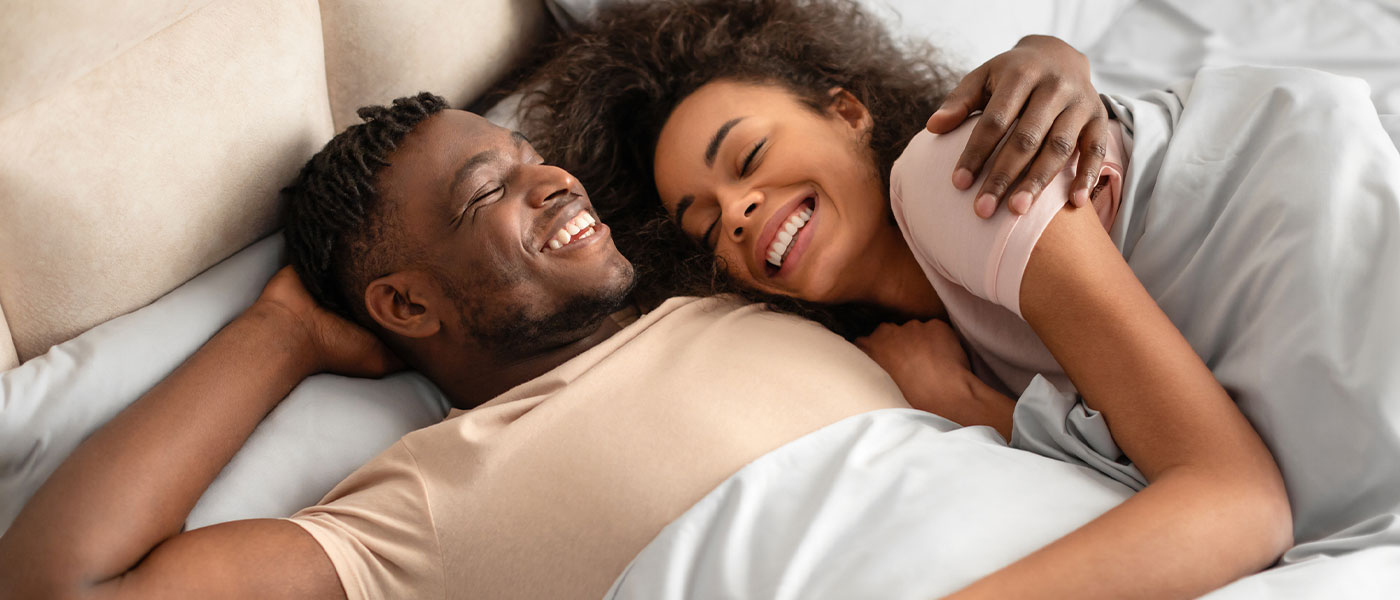 Happy couple in bed embracing after renewed intimacy from P-Shot therapy at Genesis Lifestyle Medicine.