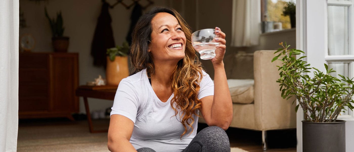 woman smiling and drinking water after taking NAD+