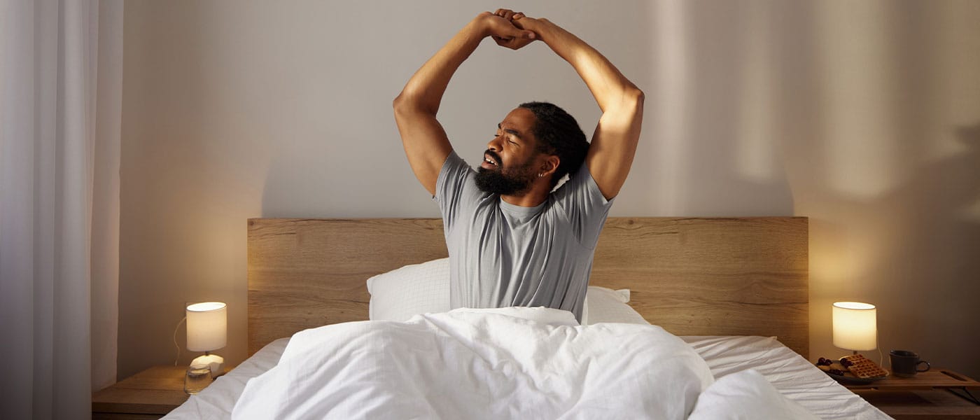 man stretching in bed after starting P-Long treatment