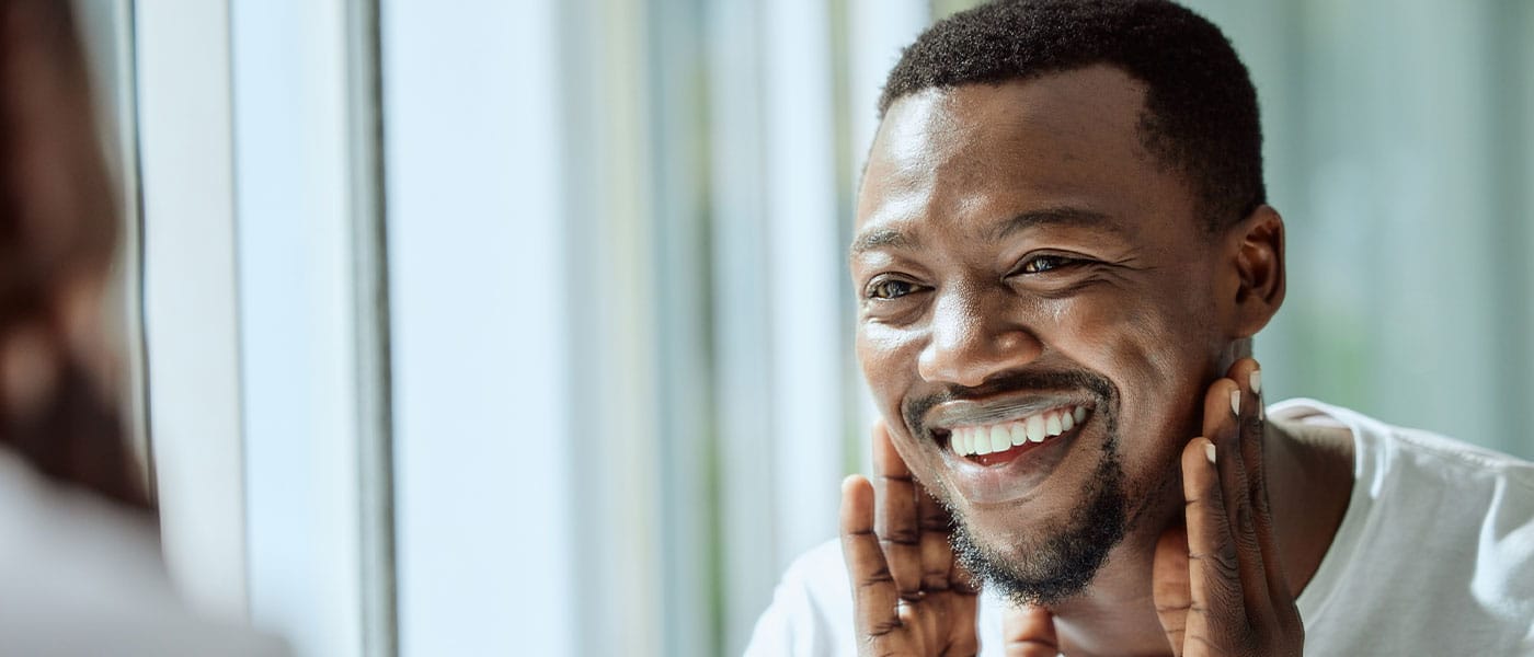 man looking at his skin in the mirror after starting sermorelin