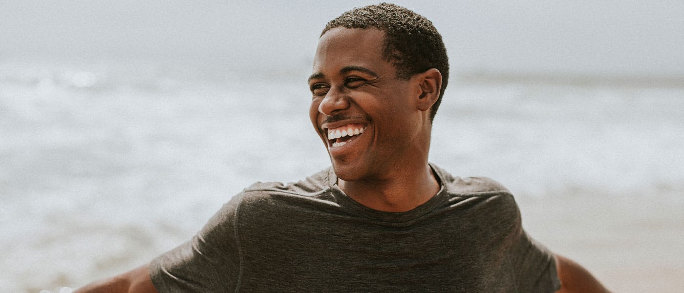 man smiling on the beach after starting P-Long treatment