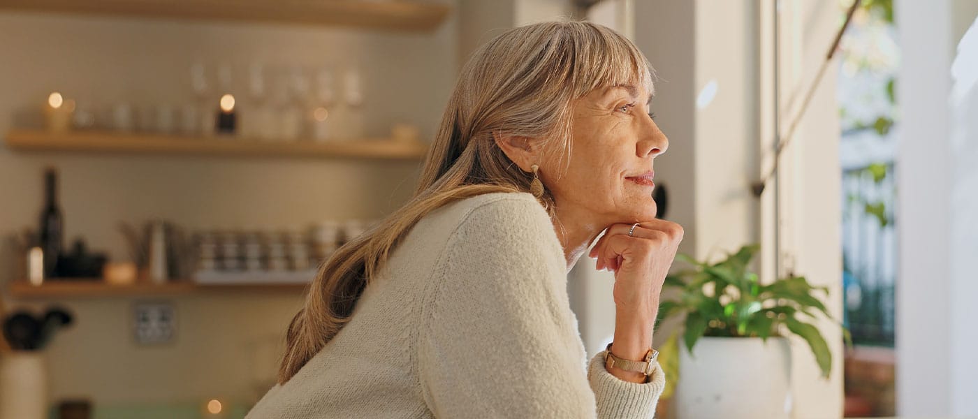 older woman looking out the window after starting hormone therapy