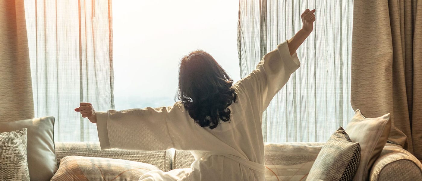 woman stretching in bed after starting hormone therapy