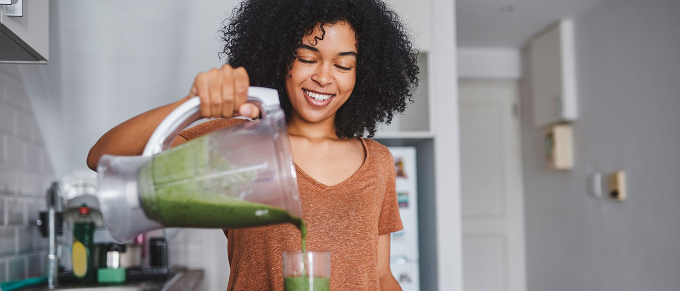 woman making a healthy shake after starting hormone therapy