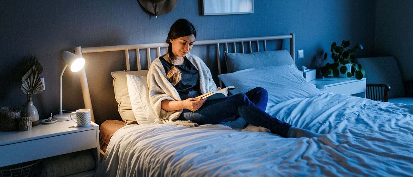 woman reading in bed after starting NAD+ therapy