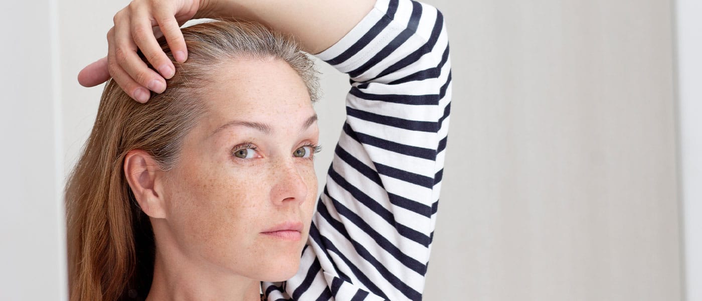 woman looking at her hair in the mirror before starting hormone therapy