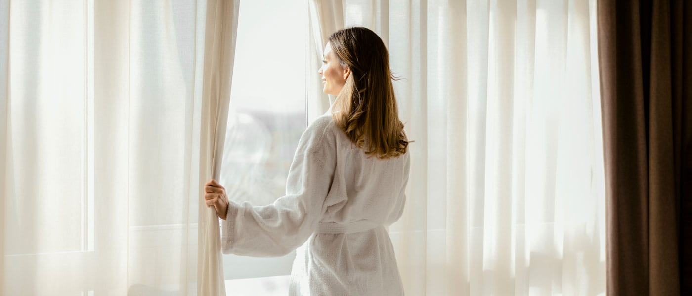 woman looking out the window after starting hormone therapy