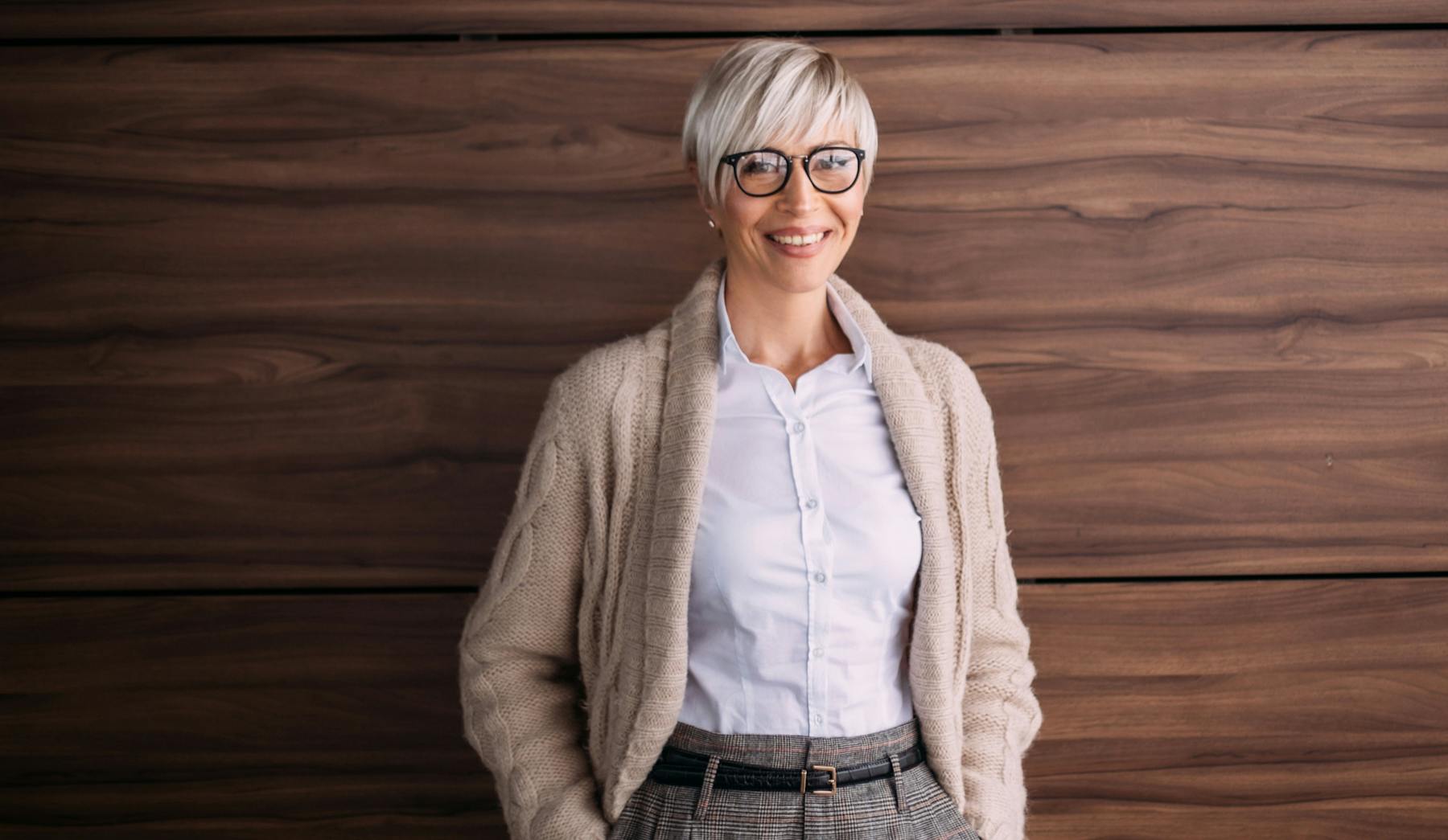 Woman that is wearing glasses, standing with her hands in her pockets