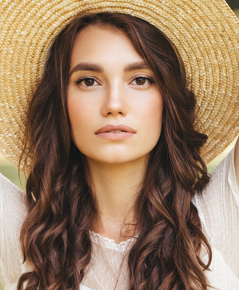 Woman that is pouting her lips and wearing a sun hat outside