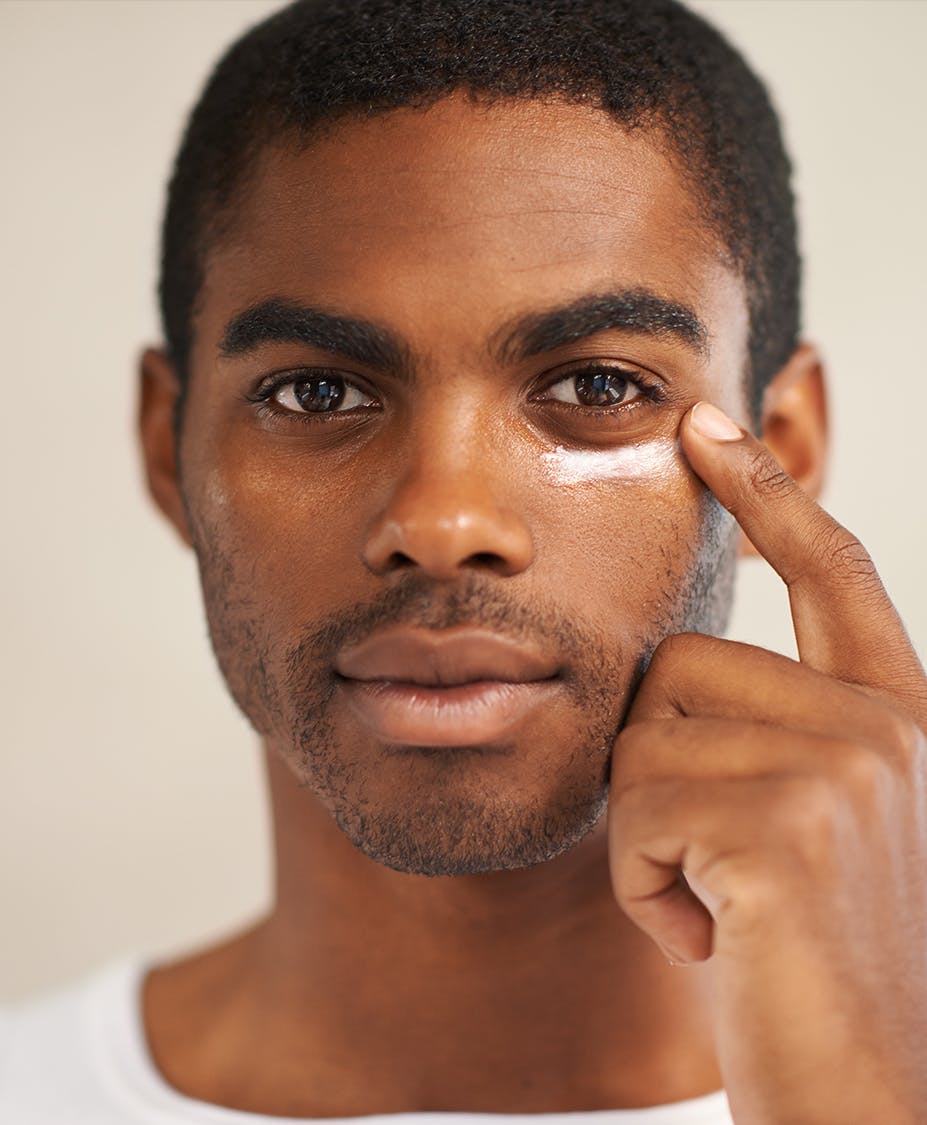 Close up photo of man's face with him pointing at his eye