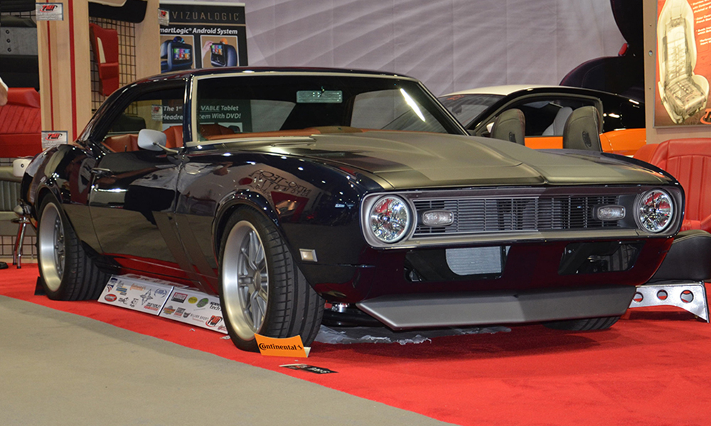 1968 Camaro Sport featuring Universal Pro Series Low Back seats with SPORT-X design including orange vinyl, orange accents, and black contrast stitching. Paired with matching rear seat and waterfall console, door panels, center console, dash pad, headliner, and carpet kit