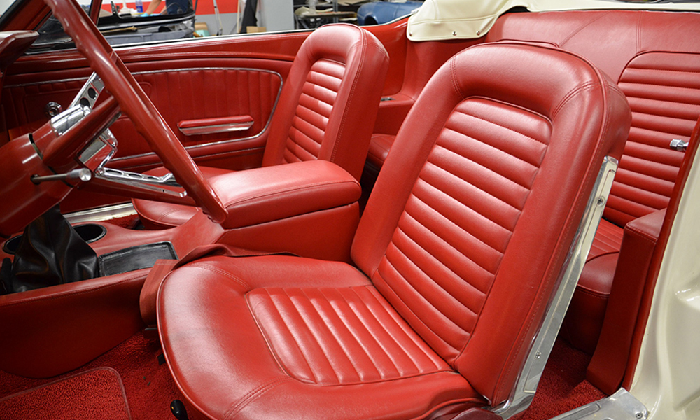 1965 Mustang featuring standard replacement bucket seats and rear seat in red. Includes matching standard door panels, carpet kit, and dash pad.