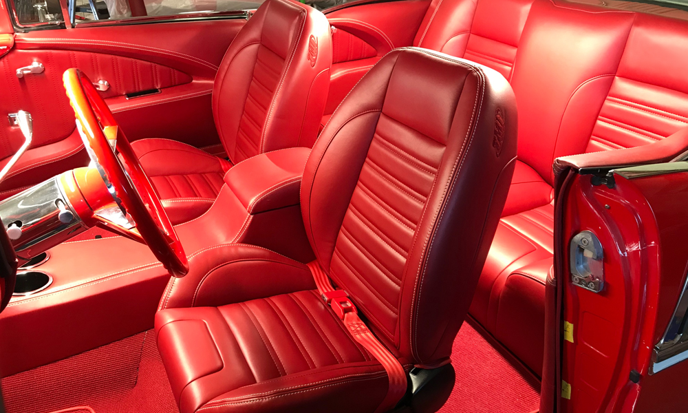 1955 Bel-Air featuring Universal Pro Series Low Back seats in SPORT design with red vinyl and white contrast stitching. Includes matching rear seat, door panels, carpet kit, dash pad, and console.