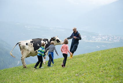 Bergbauer mit Kindern und Kuh auf der Weide