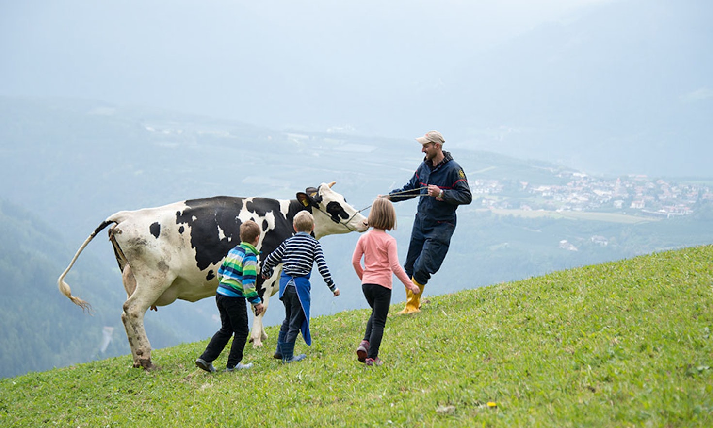 Bergbauer mit Kindern und Kuh auf der Weide