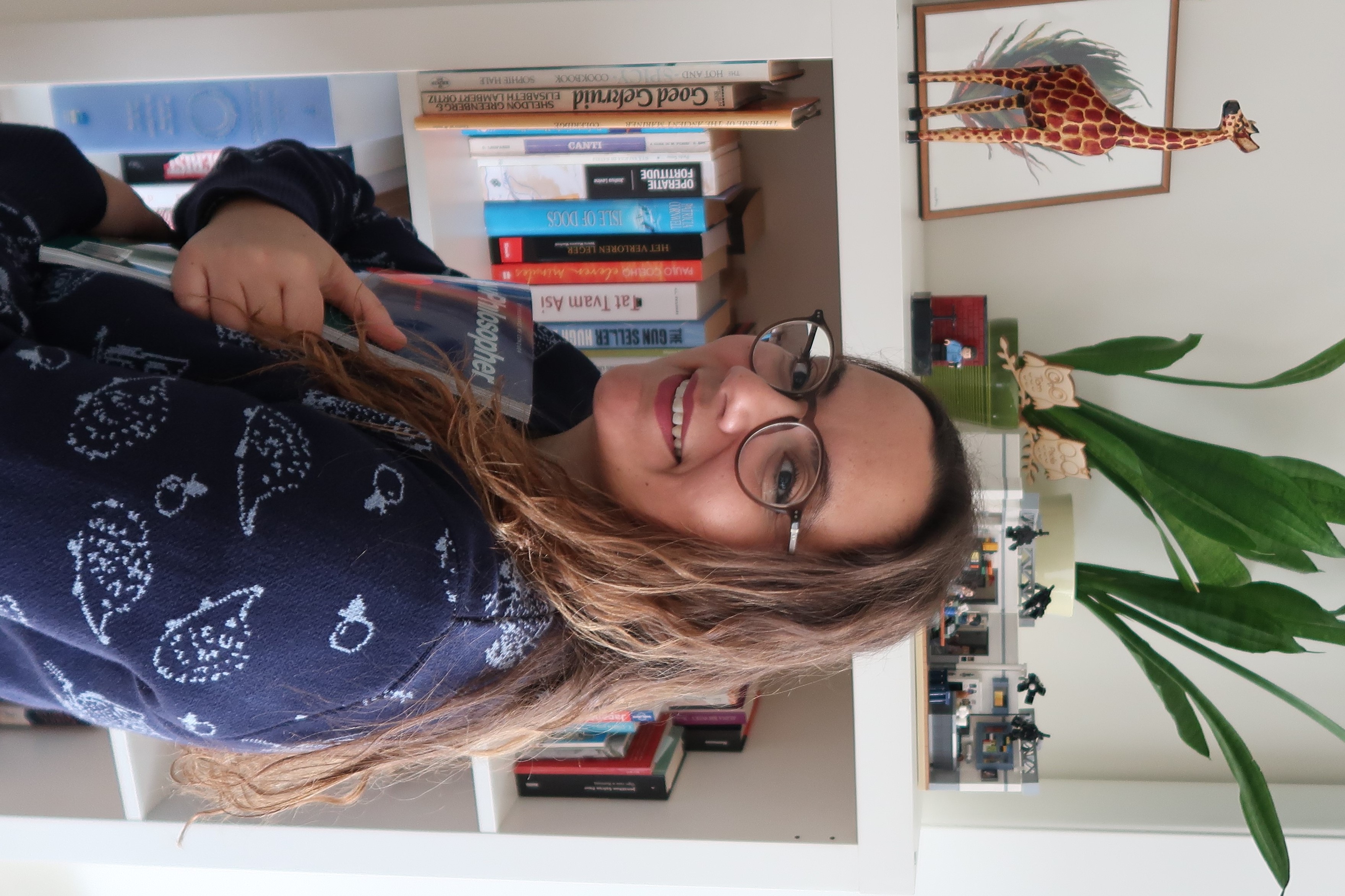 Paola Chiara Masuzzo, standing in fron of a book shelf, holding an issue of "Philosopher" magazine"