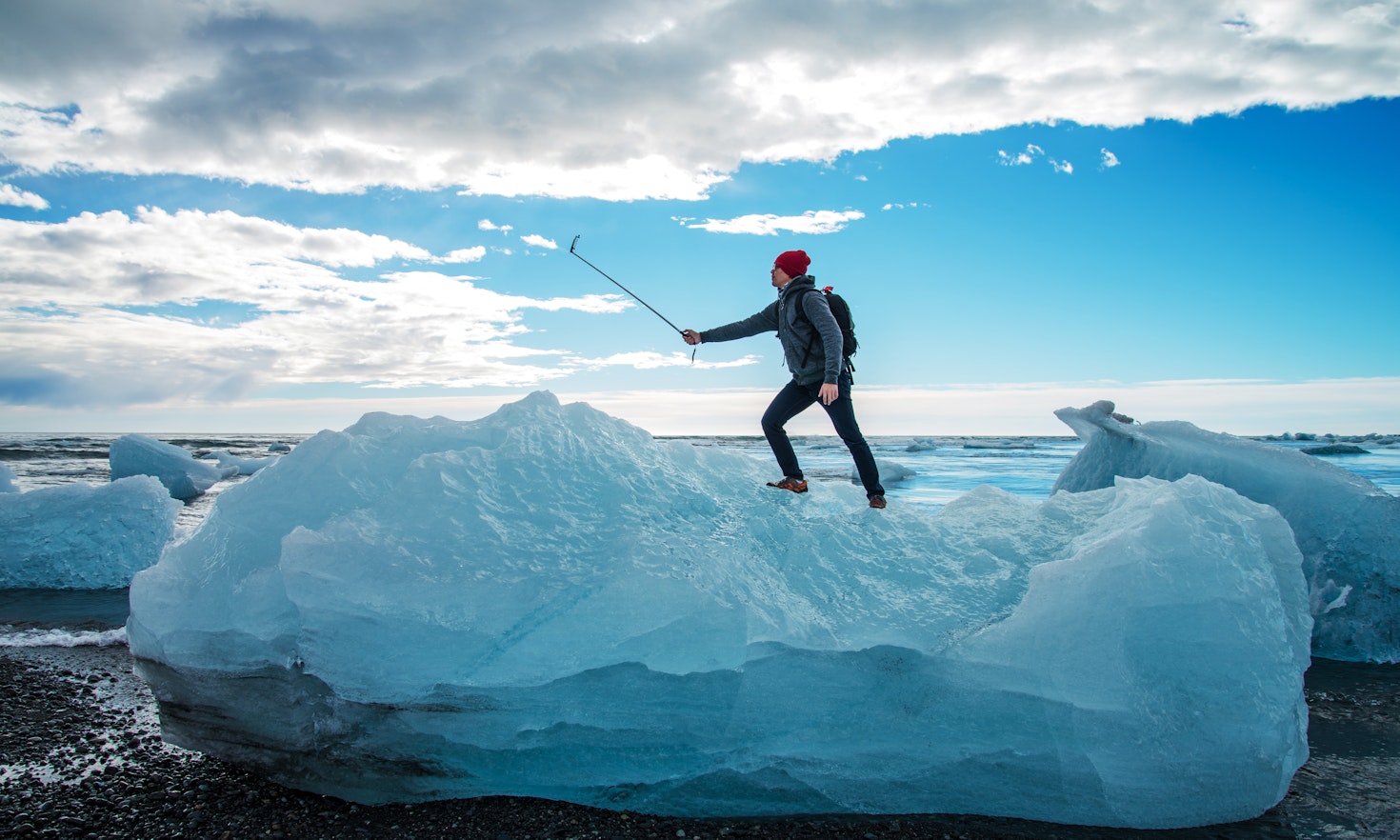Tourist man taking selfie on small iceberg Located in Diamond beach near Jokulsarlon Lagoon, Iceland