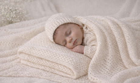 Newborn baby wrapped in a Willow & Cole cashmere blanket with matching bonnet and booties
