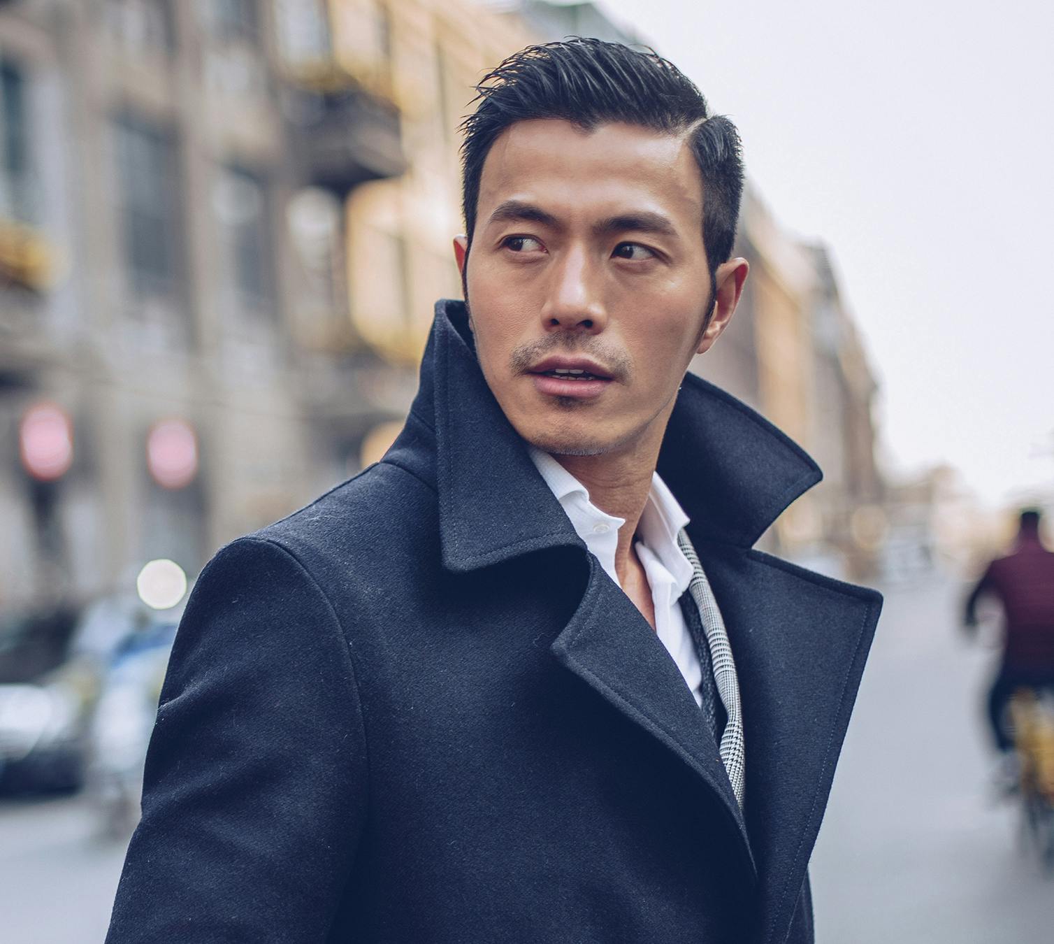 Handsome Asian man crossing the street, wearing a suit and looking to the side
