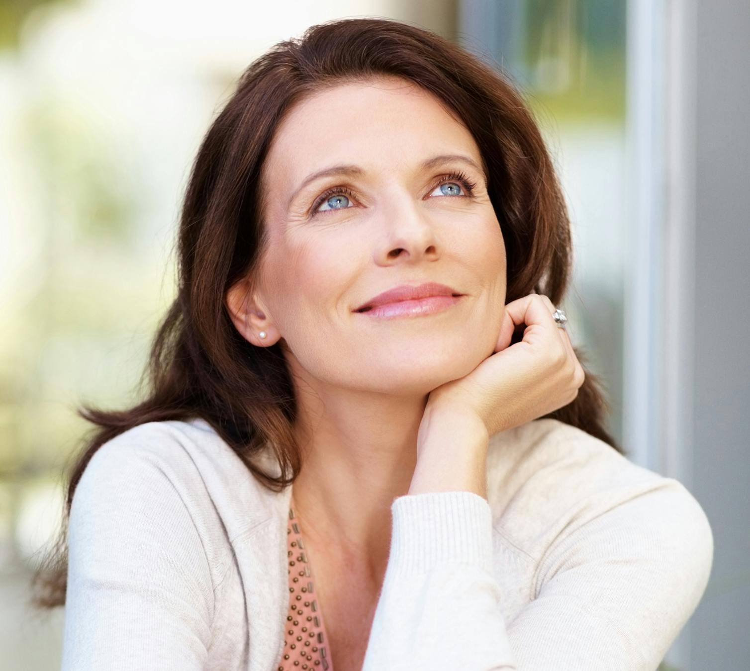 Pretty woman looking up with face resting on hand