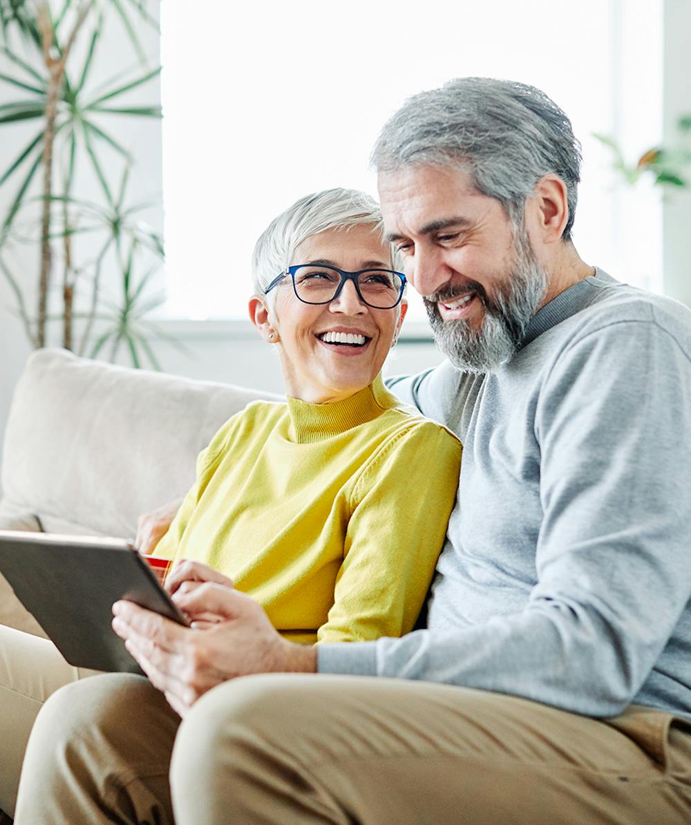 Older couple smiling and reading information on tablet