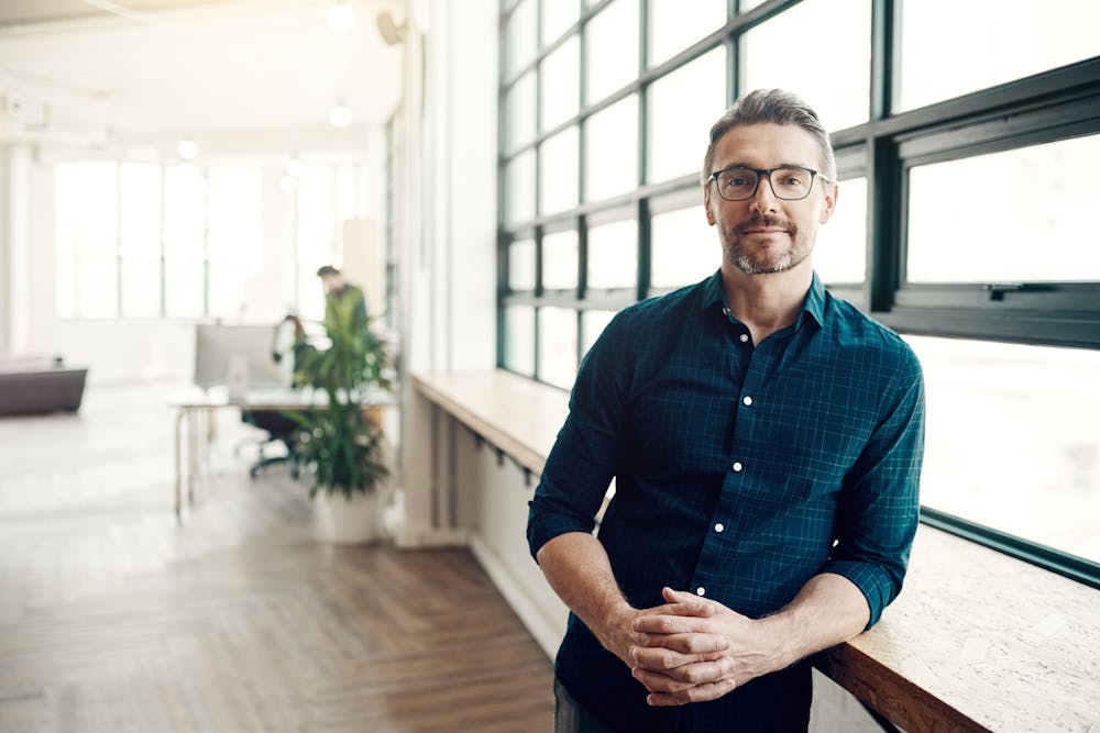 Handsome Man In A Office Leaning On A Desk.