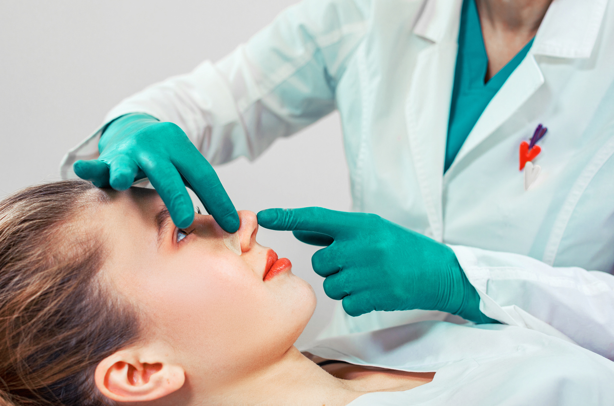 Doctor evaluating a female patient for rhinoplasty