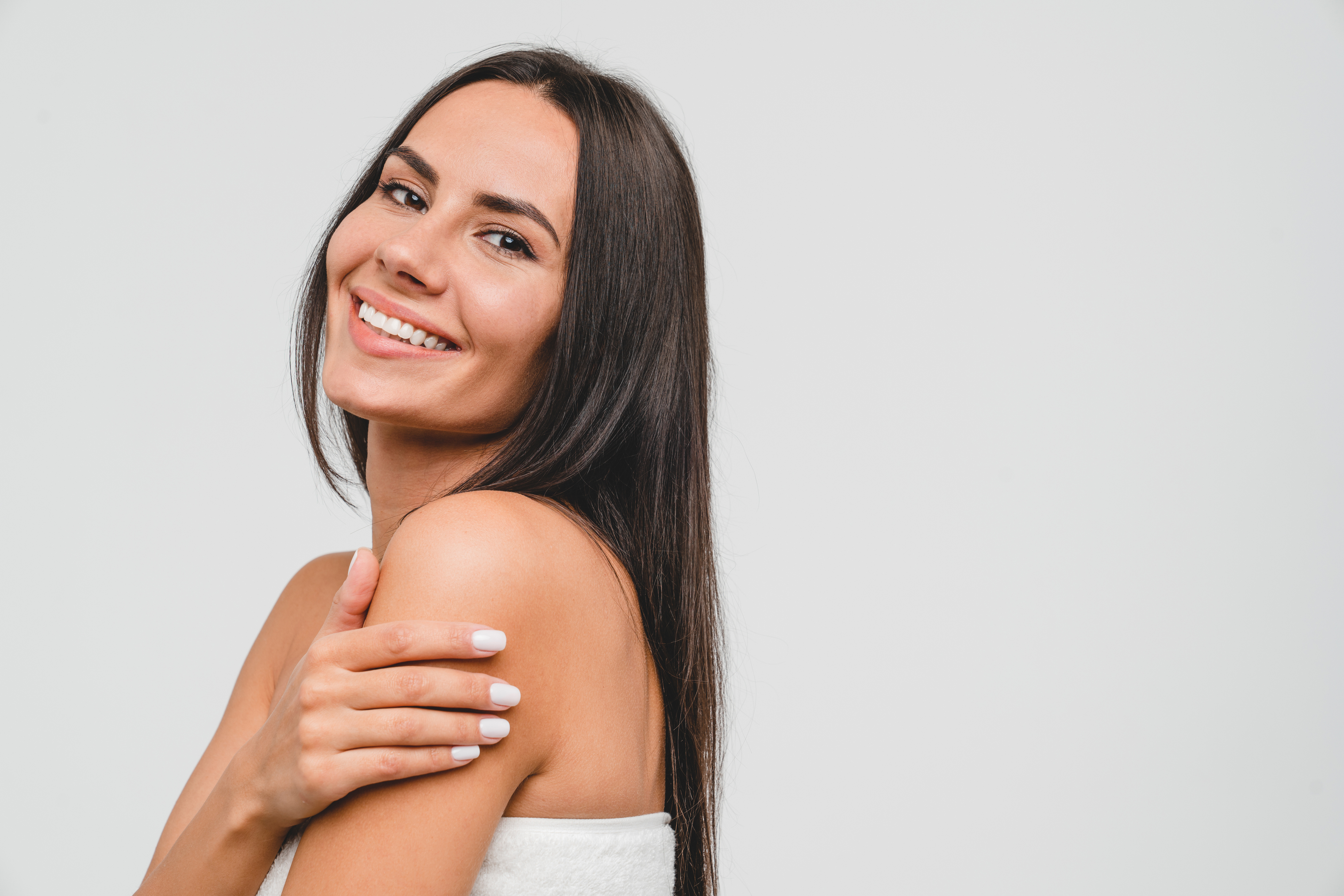 Dark-haired woman smiling holding her arm